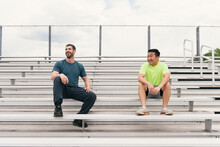 Two Men Smiling After Fitness Workout On Stadium Stairs