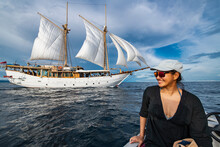 Woman Approaching Sail Boat On Dingy In Raja Ampat