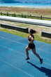 © Cavan Images - Back view of a young female sprinter running on an athletics track