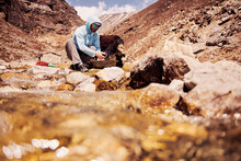 Trekker Washing His Clothes By The Stream In Nepal