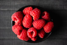 Close Up Of A Bowl Of Fresh Red Raspberries On Black Background.