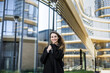 © Cavan Images - Young girl i coat stands in the city against backdrop of a business