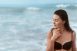 © verona_studio - Portrait of young woman in black bikini on tropical beach looking at camera. Beautiful  girl in swimwear