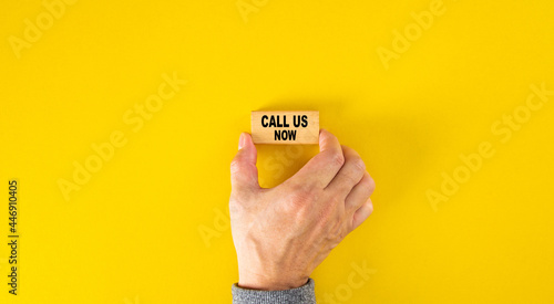 Hand holding a wooden block with text CALL US NOW
