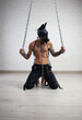 a man in a leather bdsm mask of a dog handcuffed to chains is kneeling against the wall