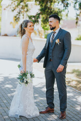 Canvas Print - Beautiful bride in a wedding dress and a groom in a stylish suit are having a photoshoot in the park