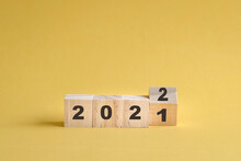 Wooden Cube Stock Flipping, Change From 2021 To 2022. Yellow Background, With Copy Space.