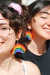 two women friends smiling with glasses wearing rainbow pride flag themed earrings *2
