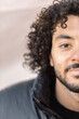 © Austockphoto - Close up and half face shot of a smiling young man with a curly hair and beard