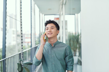 Wall Mural - Happy man speaking on cellphone standing on balcony in city in summer day