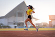 © EduLife Photos - A young Asian woman athlete runner jogging on running track in city stadium in the sunny morning to keep fitness and healthy lifestyle. Young fitness woman runs on stadium track. Sport and recreation