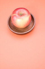 Sticker - Vertical shot of a fresh ripe apple on a wooden saucer isolated on a pink background