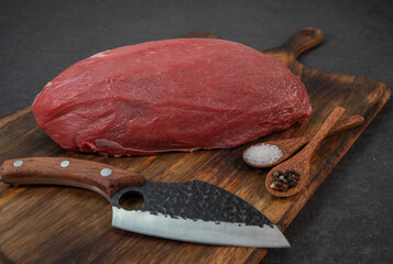 Canvas Print - A closeup of a raw beef fillet, on a wooden cutting board with spices and a sharp knife