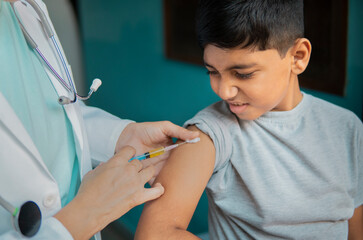 Young Indian boy receiving an injection by female doctors and shouting.  