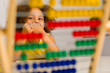 © ShunTerra - An african american student in a yellow dress laughs brightly behind a colored abacus in an elementary school