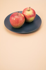 Poster - Vertical shot of apples on a plate isolated on light cream background