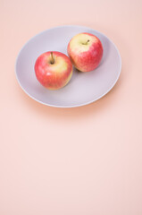 Poster - Vertical shot of apples on a plate isolated on light cream background