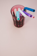 Wall Mural - Vertical shot of colorful stainless straw on a glass isolated on a light pink background