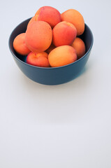 Sticker - Vertical shot of fresh apricots on a bowl isolated on white background with copy space