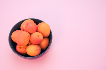 Wall Mural - Top view of fresh apricots on a bowl isolated on light pink background with copy space