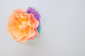 Poster - Top view of orange rose and chrysanthemum on a vase isolated on a light cream background