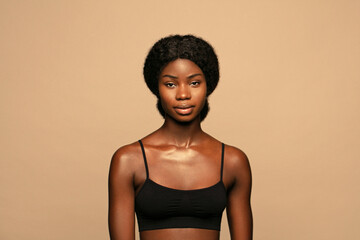 Wall Mural - young beautiful african american woman with curly hair against beige background