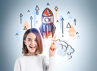 Wall Mural - Happy and confident young attractive business woman looking toward camera and wondering about startup and how to succeed. Concept of success and new business project launch. Colorful rocket sketch