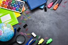 School Accessories. Magnifier, Notebooks, Markers, Pencils, Pens, Notepads, Paints And Paper Clips On A Gray Background. Top View, Copy Space. Education Concept.