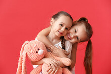 Cute Little Sisters With Toy On Color Background