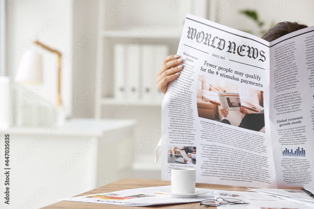 Young woman reading newspaper at home