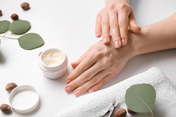 Woman applying shea butter onto hands on white background