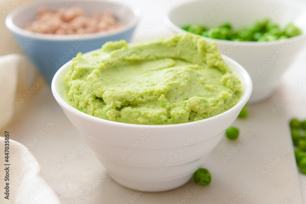 Bowl with tasty green pea hummus on table, closeup