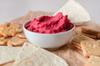Bowl with tasty beet hummus and crackers on table, closeup