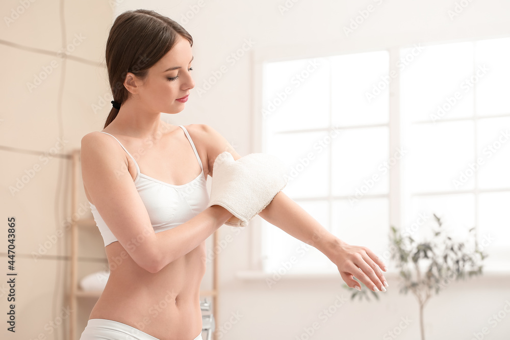 Beautiful young woman with massage mitten in bathroom - obrazy, fototapety, plakaty 