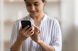 © fizkes - Close up cropped of Indian woman using phone, typing on screen, writing message in social networks, young female browsing mobile device apps, shopping or chatting online, holding smartphone