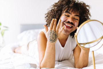 Wall Mural - Gender nonconforming man applying makeup to his face