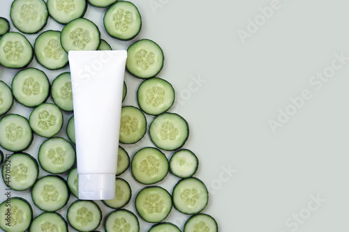 Mockup of white squeeze eco friendly plastic tube and cucumber slices on light green background. Front view. Clean beauty concept. Flatlay, mock-up, template.