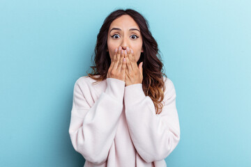 Wall Mural - Young mexican woman isolated on blue background shocked covering mouth with hands.