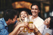 © djile - Group of young people at a summer bar toast with beer. Selective focus on beer.