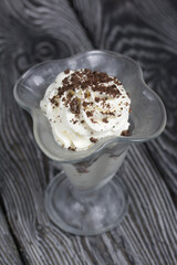 Wall Mural - Dessert with cream and blueberries. Decorated with chocolate drops. In glass goblets. On black pine boards.