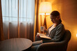 © Anton - Cozy evening at home.A young woman is sitting in a chair and reading a book. She has a cup of tea in her hand. In the corner of the room, a floor lamp burns with a soft yellow light.
