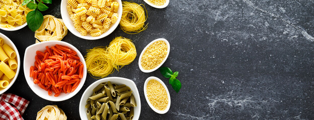 Poster - Pasta. Various kinds of uncooked pasta and noodles over stone background, top view with copy space for text. Italian food culinary concept. Collection of different raw pasta on cooking table. Banner.