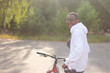 © Alexander - A happy African-American man is walking down the street with a bicycle