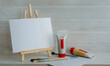 Creative workshop, artist's workplace, art studio. Wooden table easel, white blank canvas, brushes and paints in tubes on the background of a wooden wall.