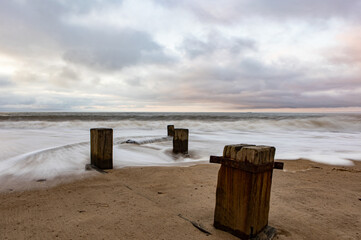 Sticker - . Beautiful view of port wooden posts near the water under cloudy silver sky in the morning