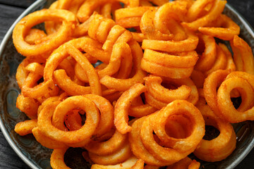 Wall Mural - Golden Spicy Seasoned Curly Fries on rustic plate. ready to eat