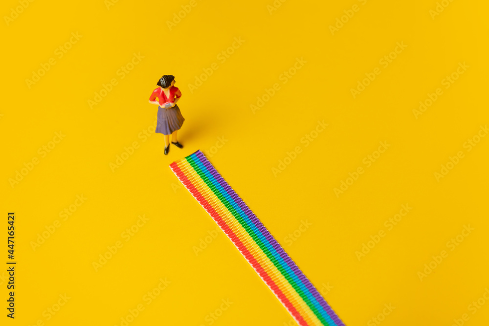 Adult woman figure stand on rainbow LGBT strip on yellow background - obrazy, fototapety, plakaty 