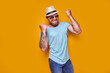 © zamuruev - Image of excited bearded tattooed man in sunglasses and hat making winner gesture isolated yellow background.
