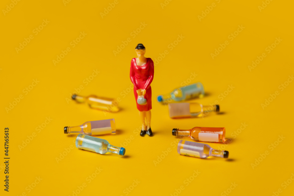 miniature figure of a woman with alcohol bottles around of her - obrazy, fototapety, plakaty 
