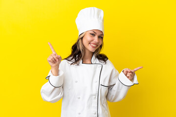 Young Russian chef girl isolated on yellow background pointing finger to the laterals and happy